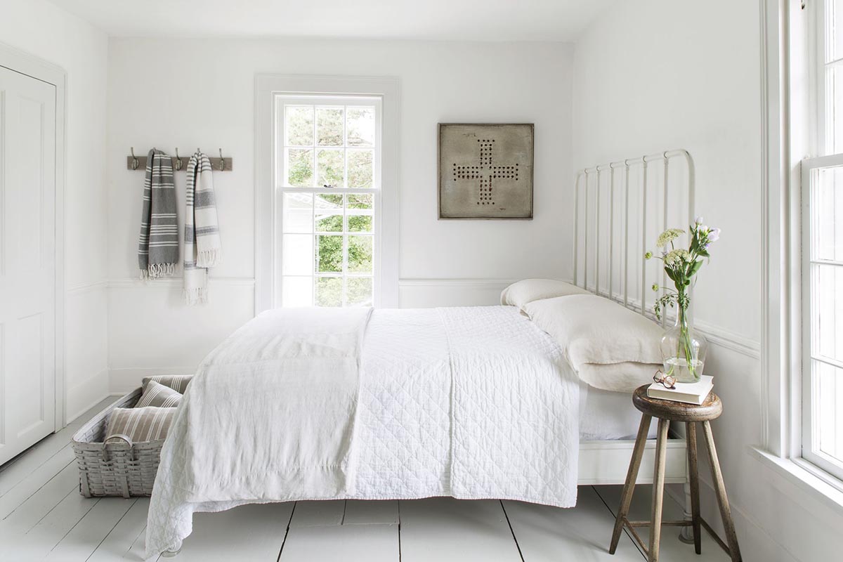 Một chiếc giường với bộ ga gối trắng tinh khiết khiến căn phòng trở nên sáng và rộng hơn